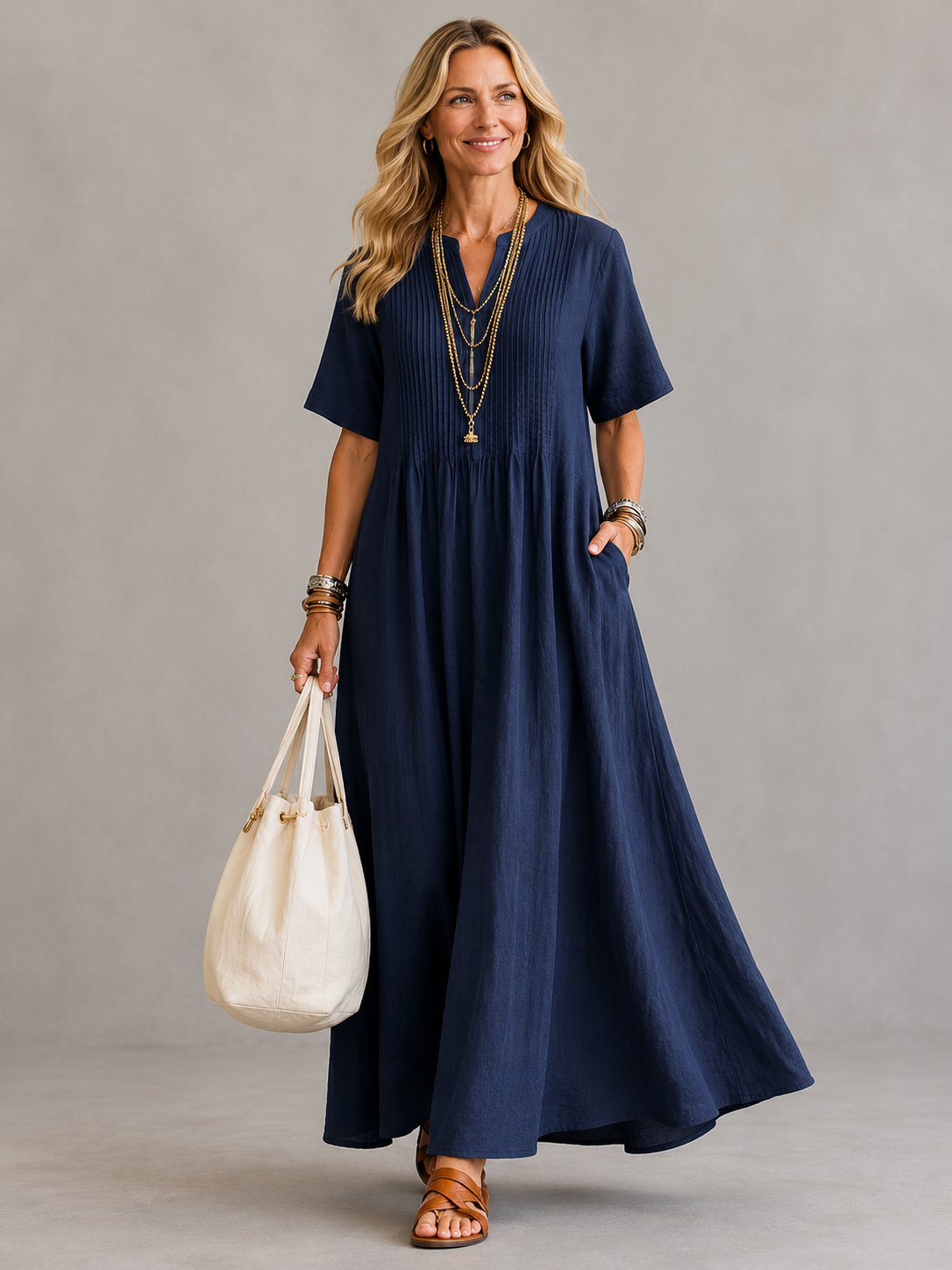 Natasha pleated maxi dress in marine blue, full-length front view with hand in pocket