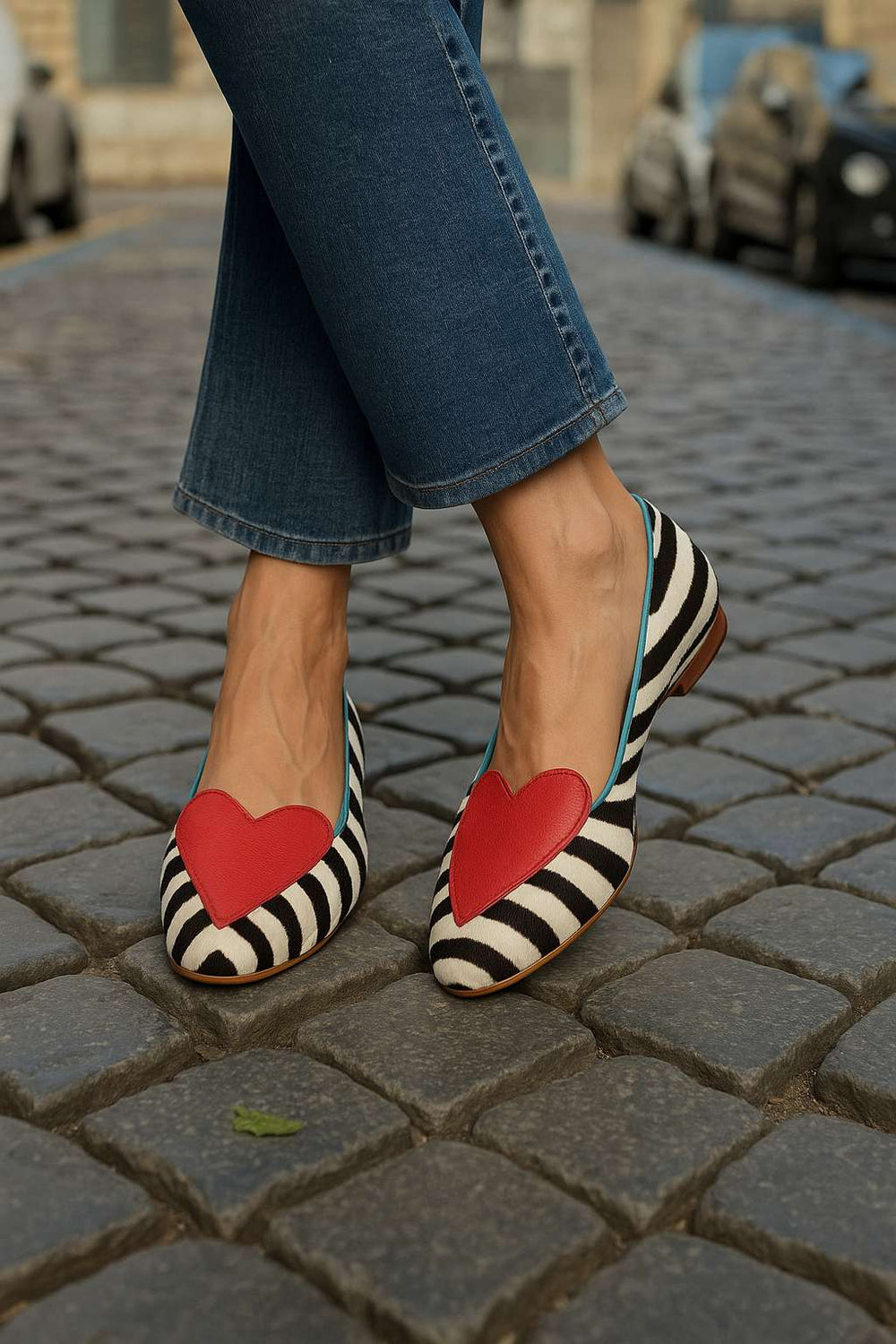 Zebra print pointed-toe ballet flats with red heart detail, worn street view