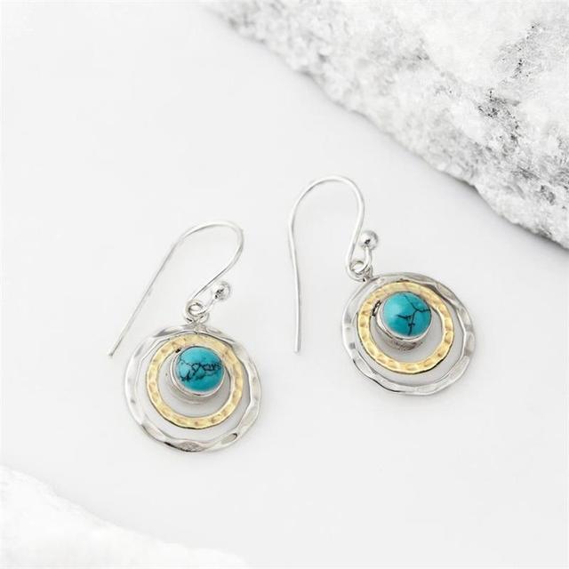 Pair of boho Saturn earrings in silver and gold with turquoise stones, flat view