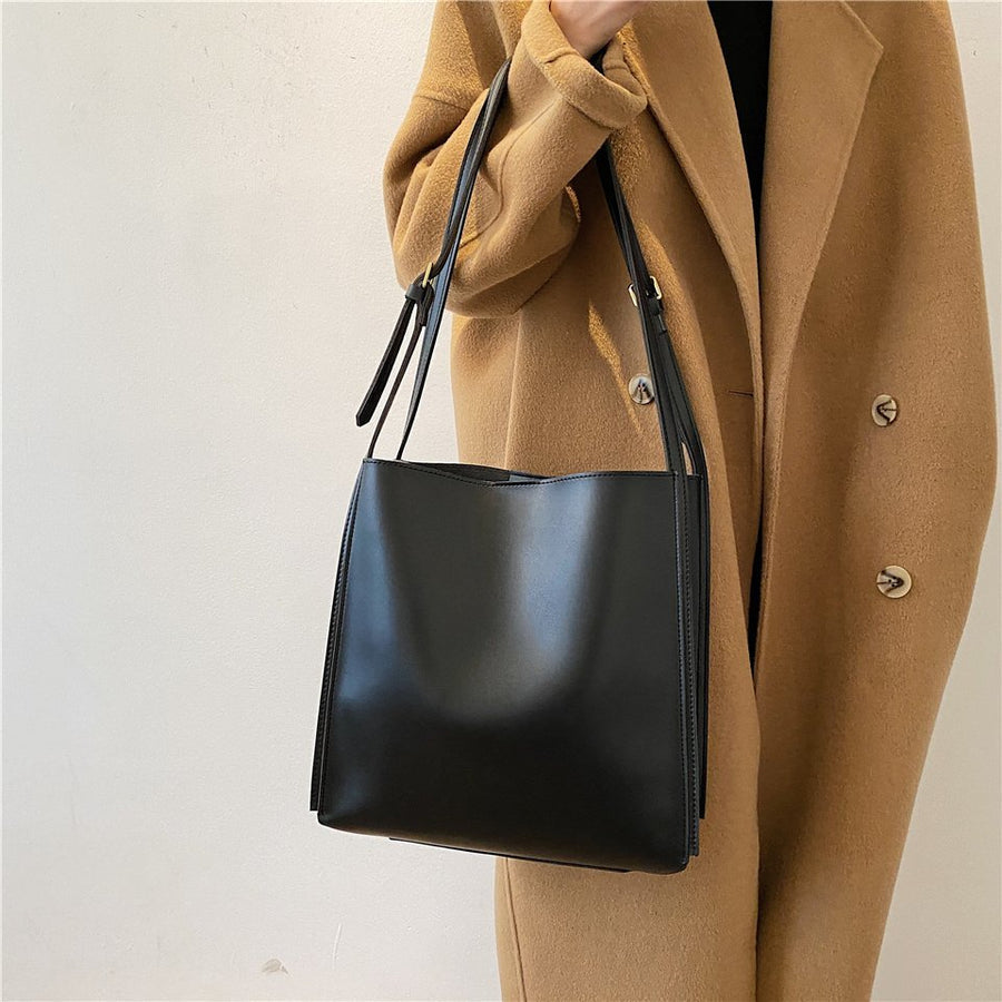 Viviana bag in black held at the side, styled with a camel coat