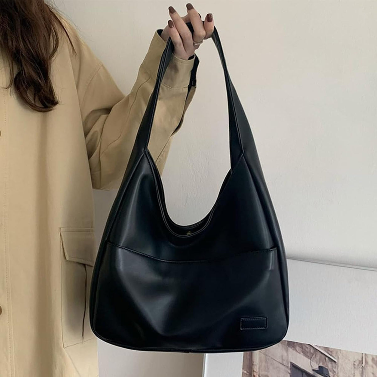 Fiora bag in black carried by the strap, side view