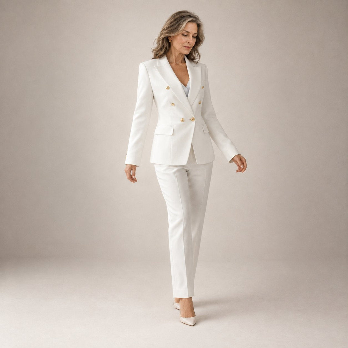 Octavia double-breasted trouser suit in white with gold buttons, full-length walking view