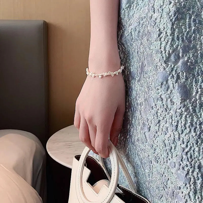 Classic pearl bracelet worn on the wrist, close-up while holding a bag