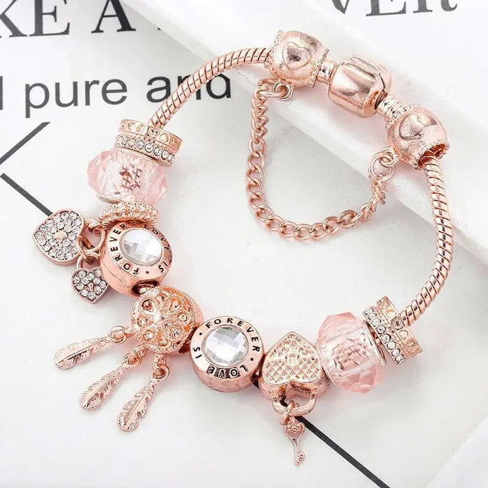 Rose gold dreamcatcher charm bracelet with pink beads and crystal hearts, close-up view