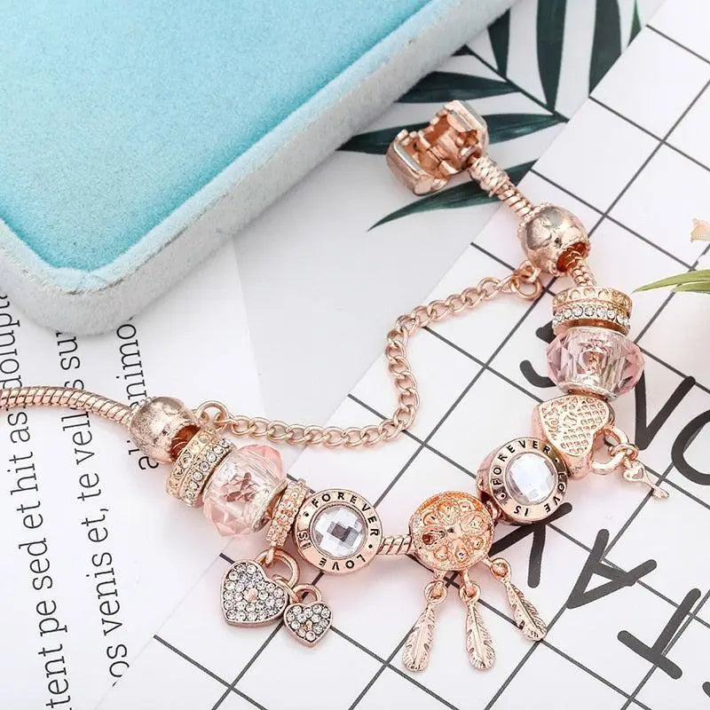 Rose gold charm bracelet with feather dreamcatcher beside a jewellery box