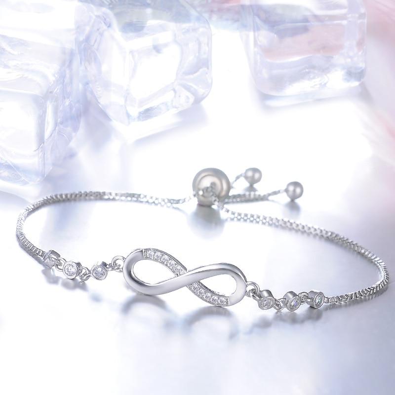 Silver infinity symbol bracelet styled beside clear ice cubes, close view