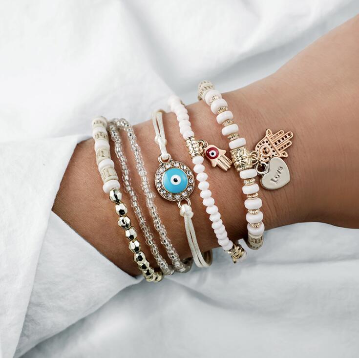 Hamsa bracelet set in white and gold, worn stacked on the wrist
