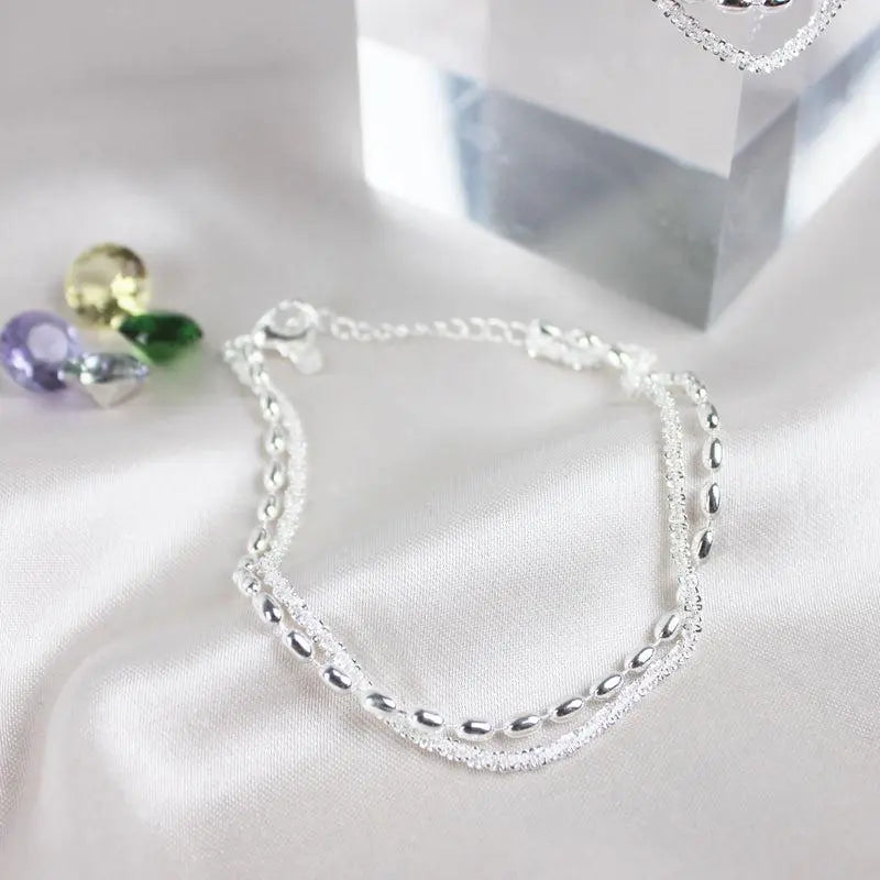Silver bracelet set in silver, close flat view on pale fabric