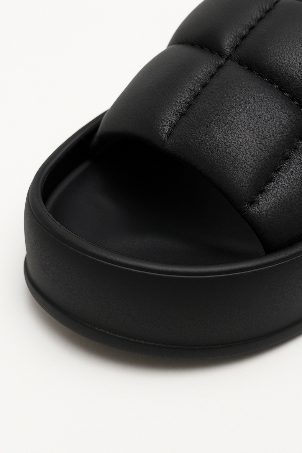 Close-up of quilted padded strap on black platform sandals