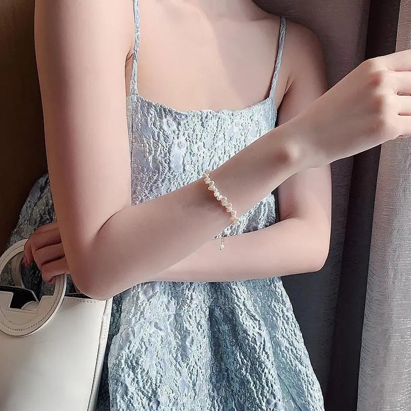 Classic pearl bracelet worn on the wrist with a pale blue lace dress
