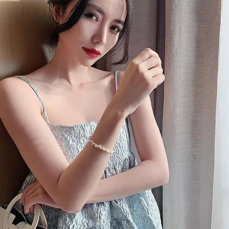 Model wearing the classic pearl bracelet with a pale blue dress, front view