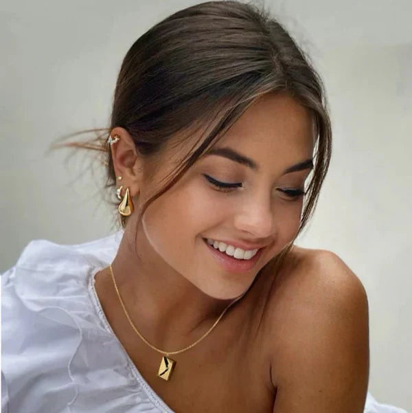 Gold envelope pendant necklace worn at the collarbone