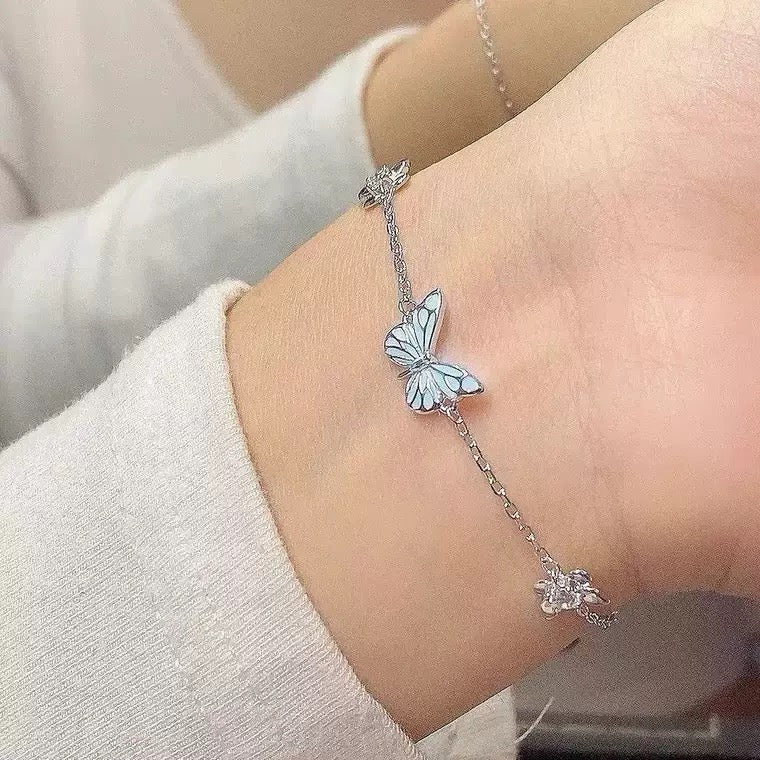 Blue butterfly bracelet worn on wrist, close-up of enamel charm