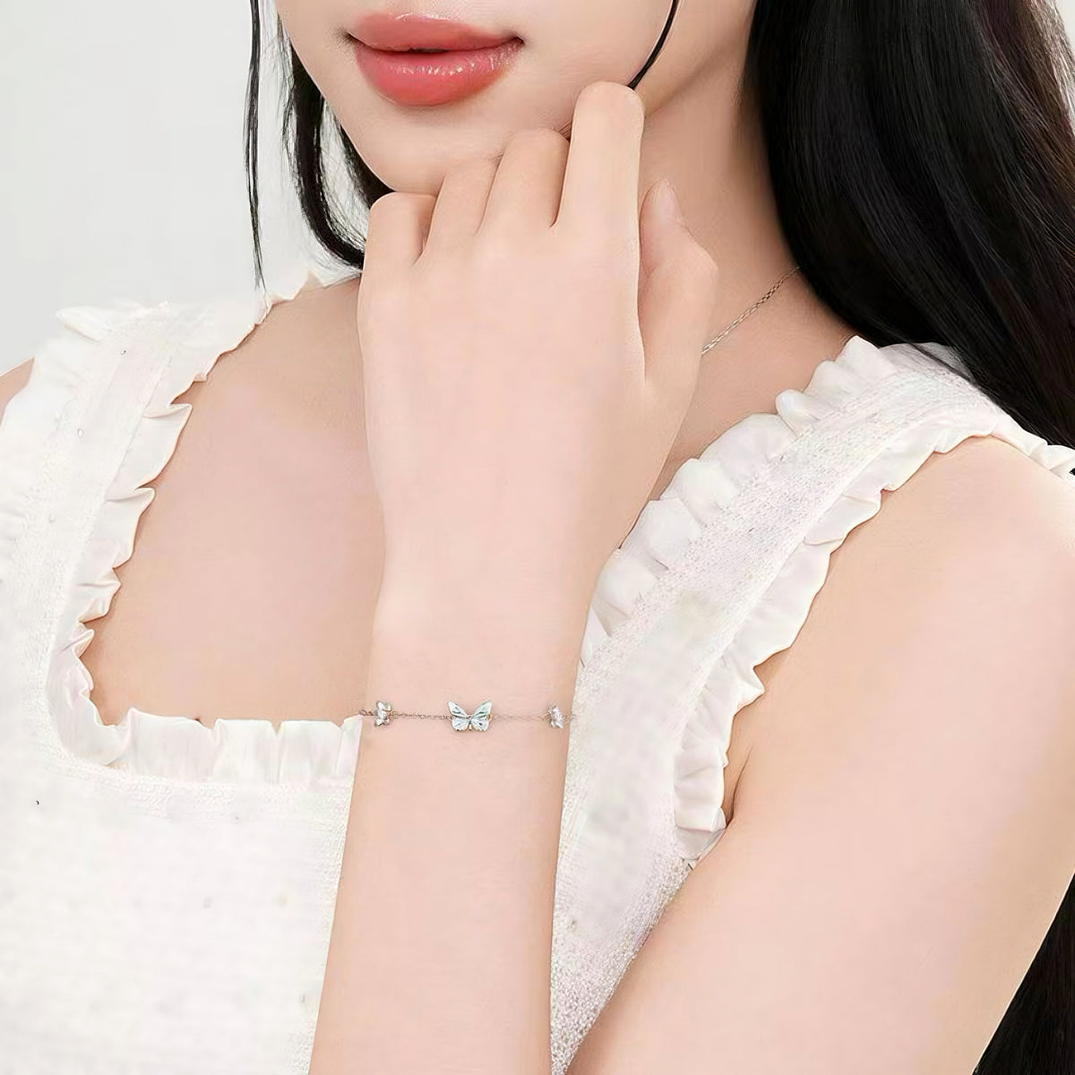 Butterfly bracelet worn on model's wrist with white ruffled top
