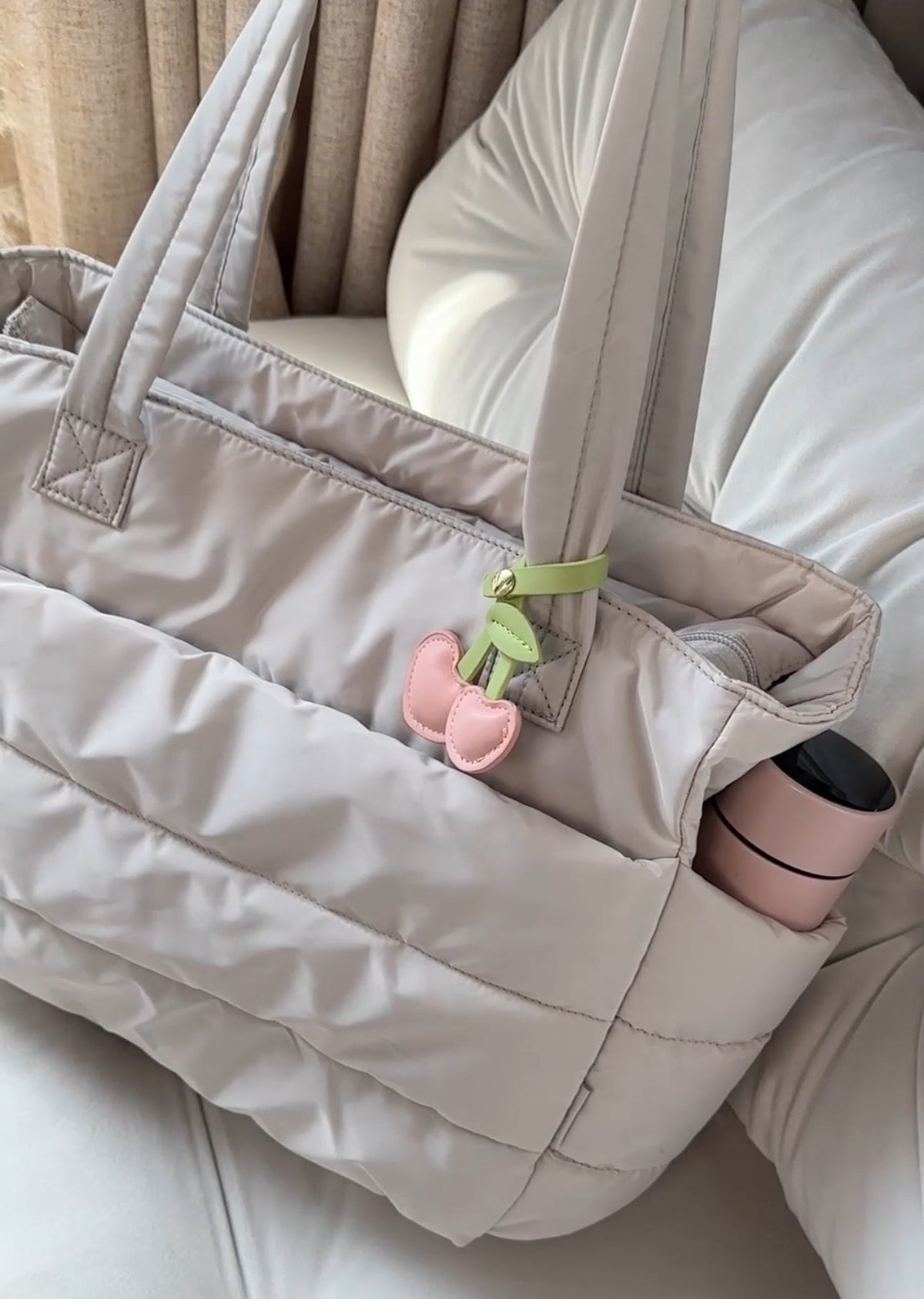 Calyss quilted shoulder bag in beige, close-up of side pocket and charm