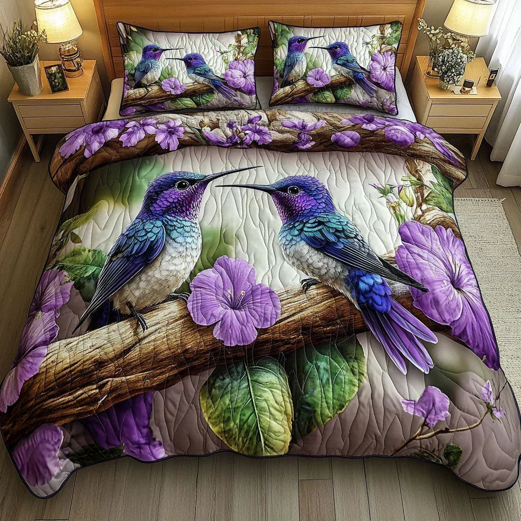 Bird Sanctuary quilted bedding set with purple hummingbirds and flowers, styled on a bed