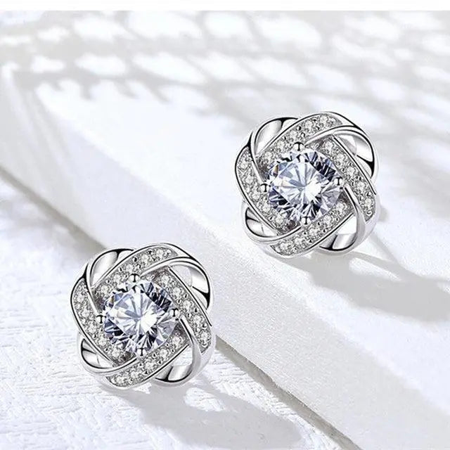 Silver-tone floral spiral stud earrings with centre gem, close-up view