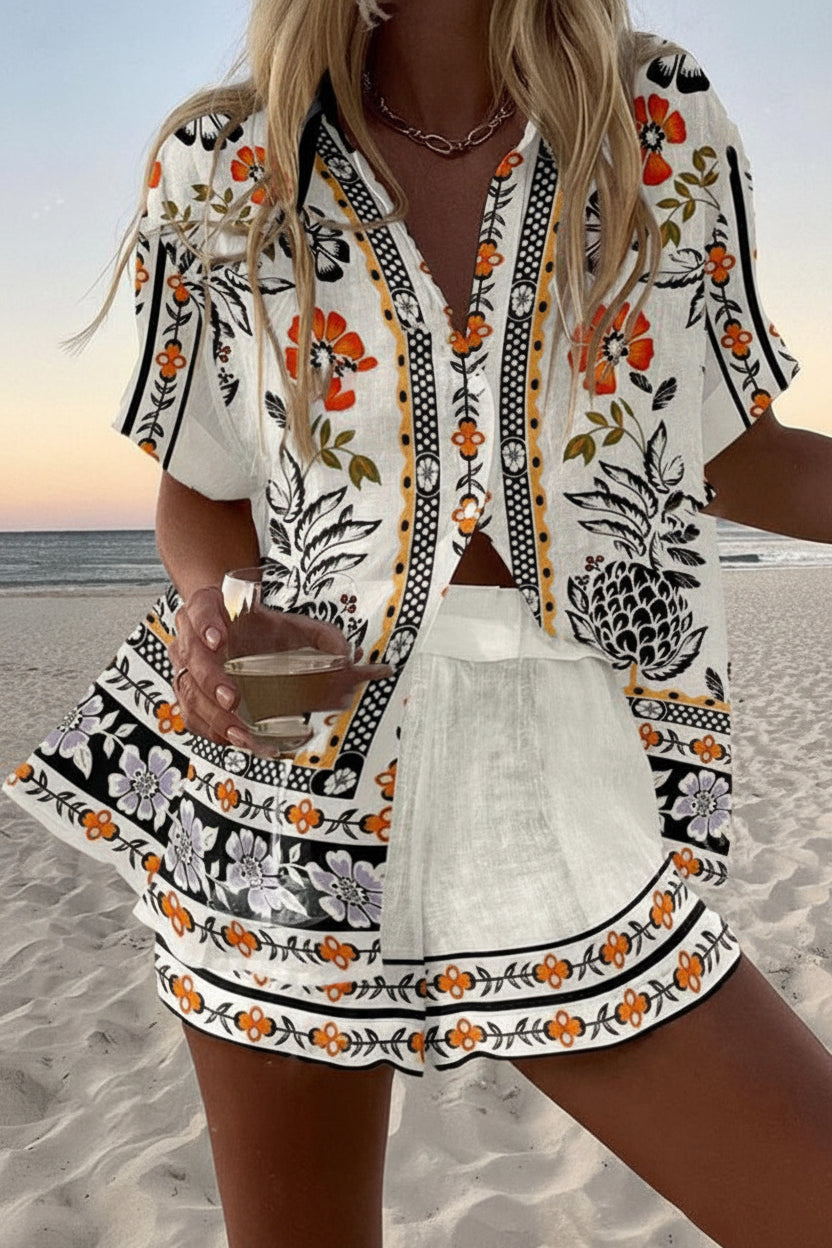 Seviglia summer co-ord set in white with orange folk print, front view on the beach