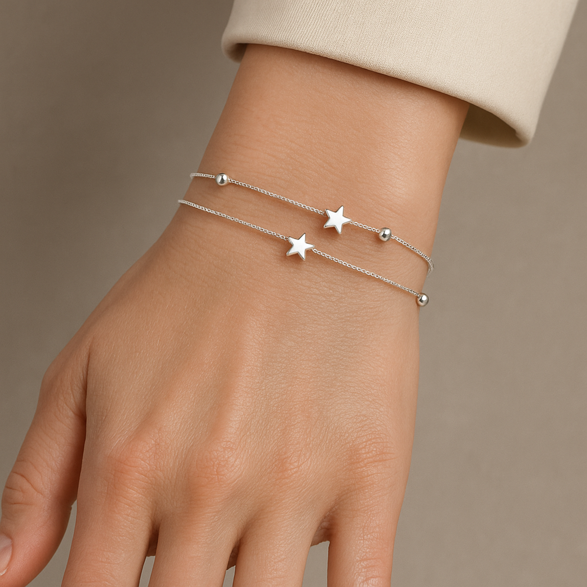 Silver double-chain bracelet with two star charms worn on the wrist