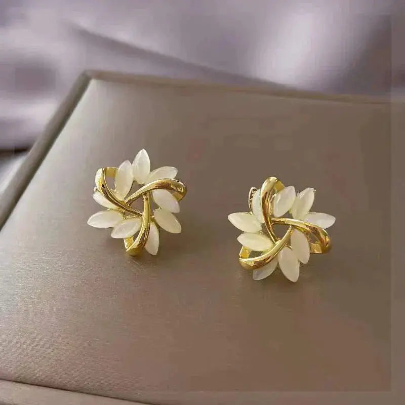 Gold stud earrings with white opal leaf detail, close-up view