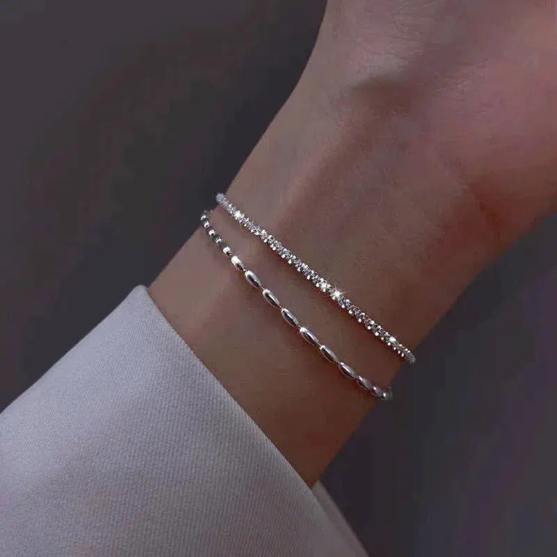 Silver bracelet set with zirconia details worn layered on the wrist
