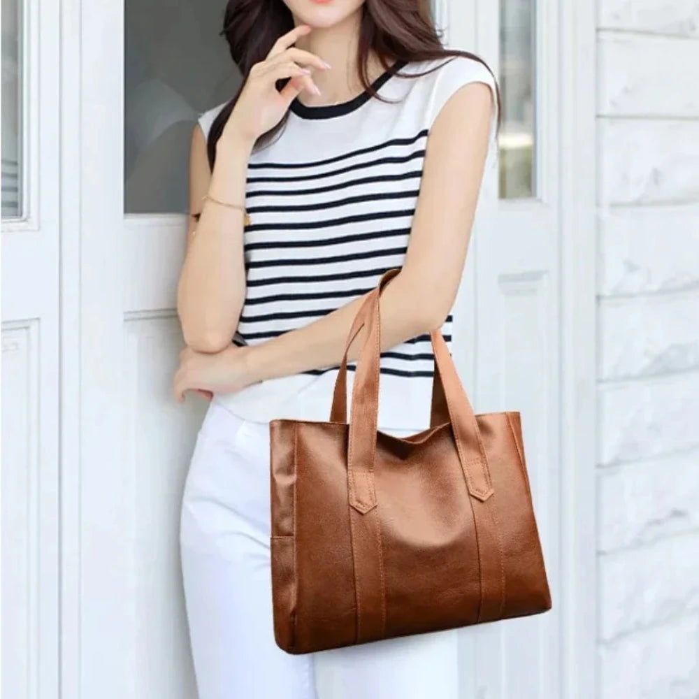 Susan shoulder bag in brown carried by a model in white trousers