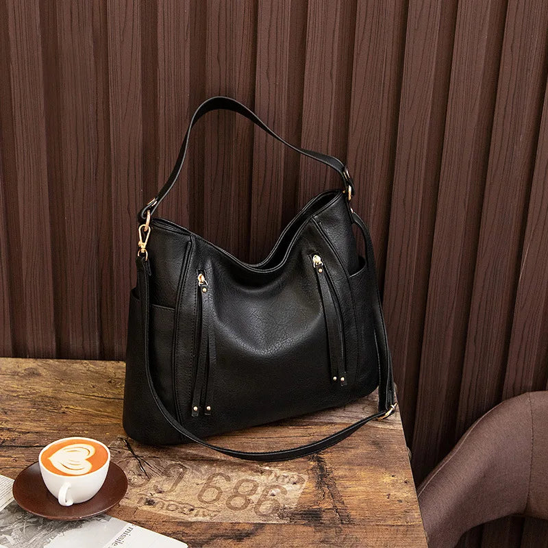 Calista luxe shoulder bag in black, styled on a wooden table