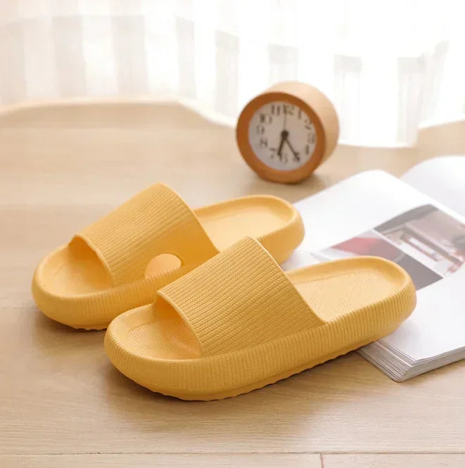 Yellow platform slide slippers on wooden floor, angled view