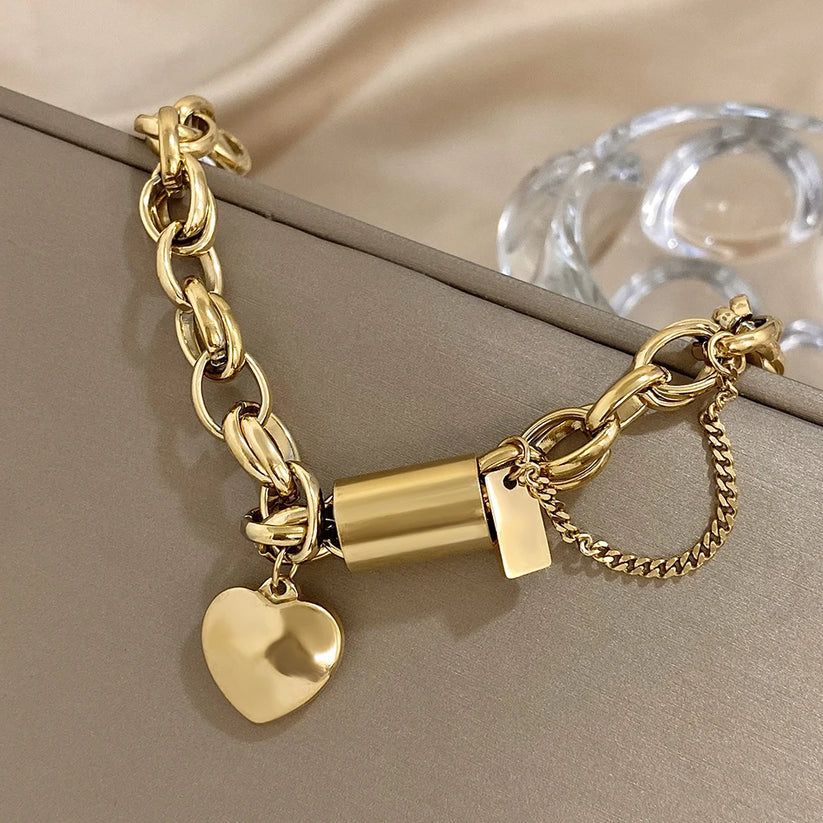 Close-up of gold bracelet centre bar, heart charm and safety chain