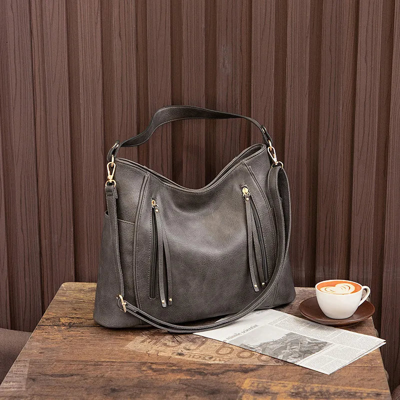 Calista luxe shoulder bag in grey, styled on a wooden table