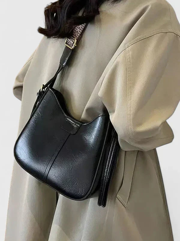 Verena shoulder bag in black worn over the shoulder with a trench coat