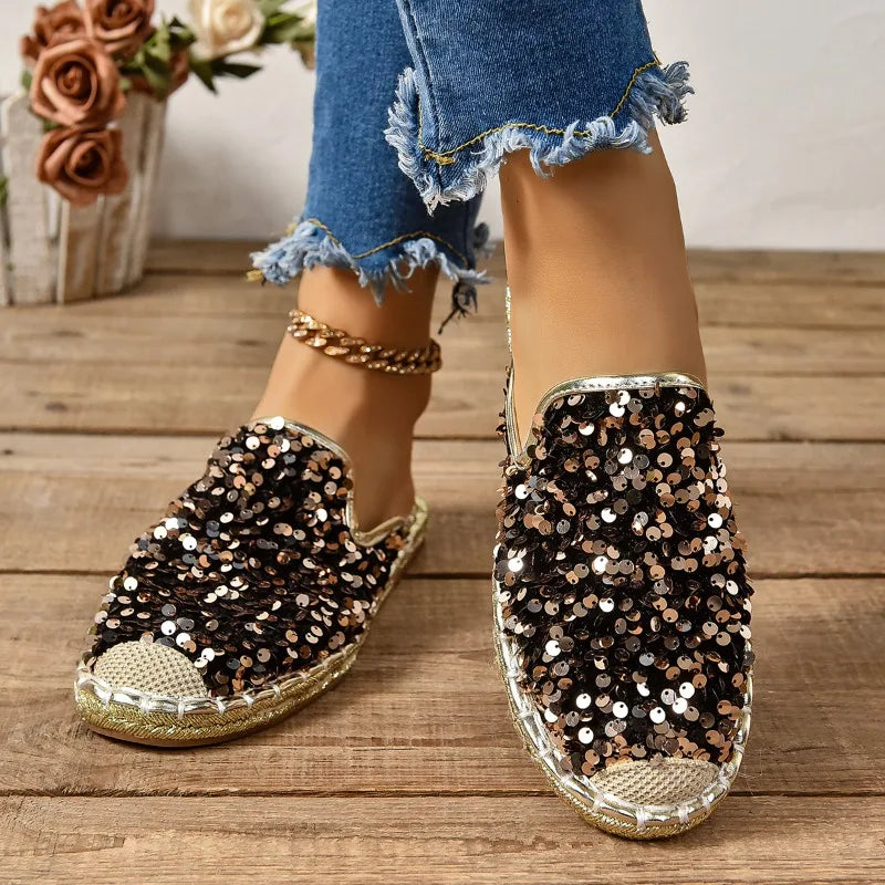 Sequinned slip-on flats in black and gold, worn side view