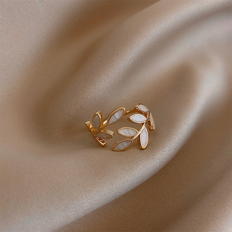 Leaf and opal adjustable ring in gold, side angle on satin fabric