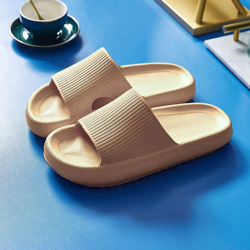 Beige platform slide slippers on blue background, angled view