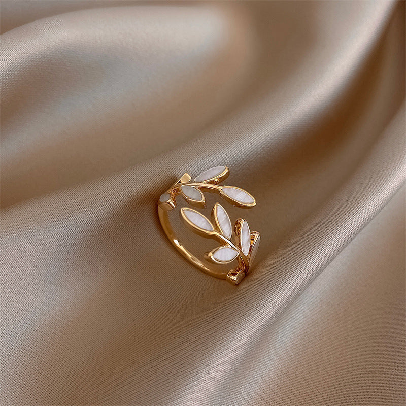 Leaf and opal adjustable ring in gold, close-up on satin