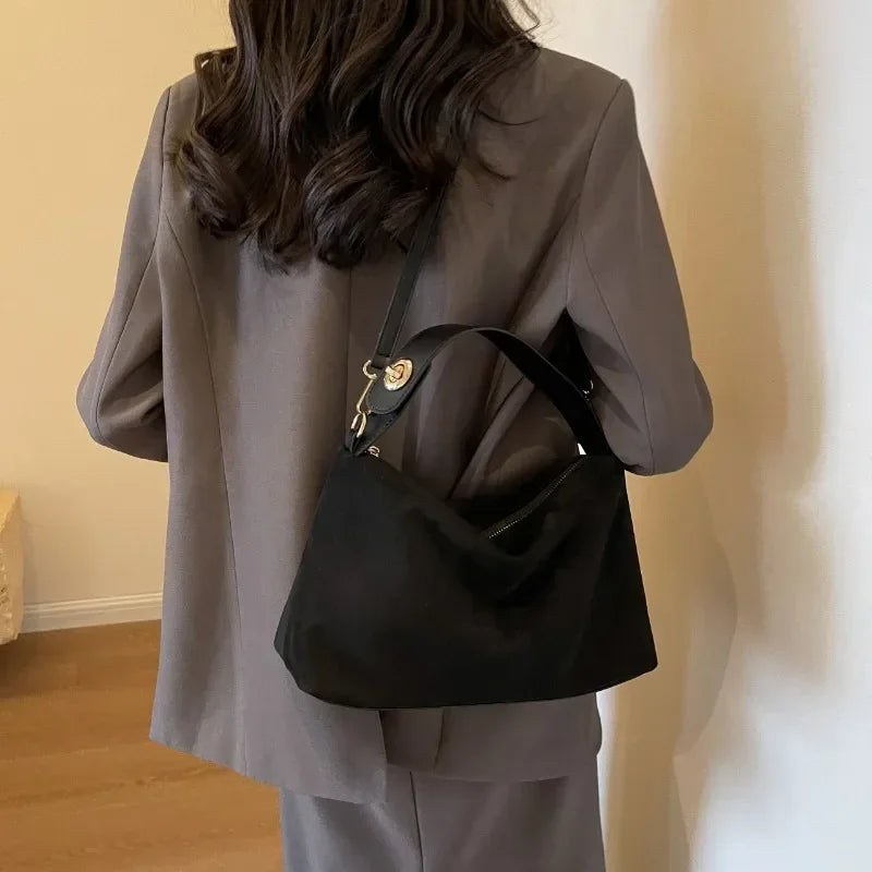 Marielle shoulder bag in black, carried on the shoulder with grey suit