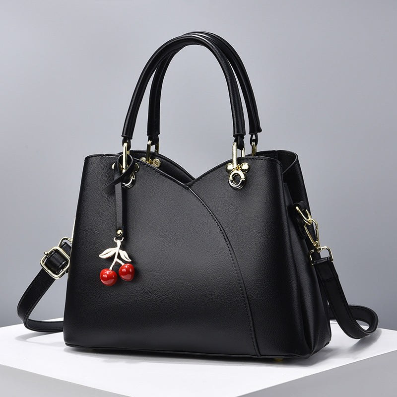 Avyra cherry tote bag in black, front view with cherry charm