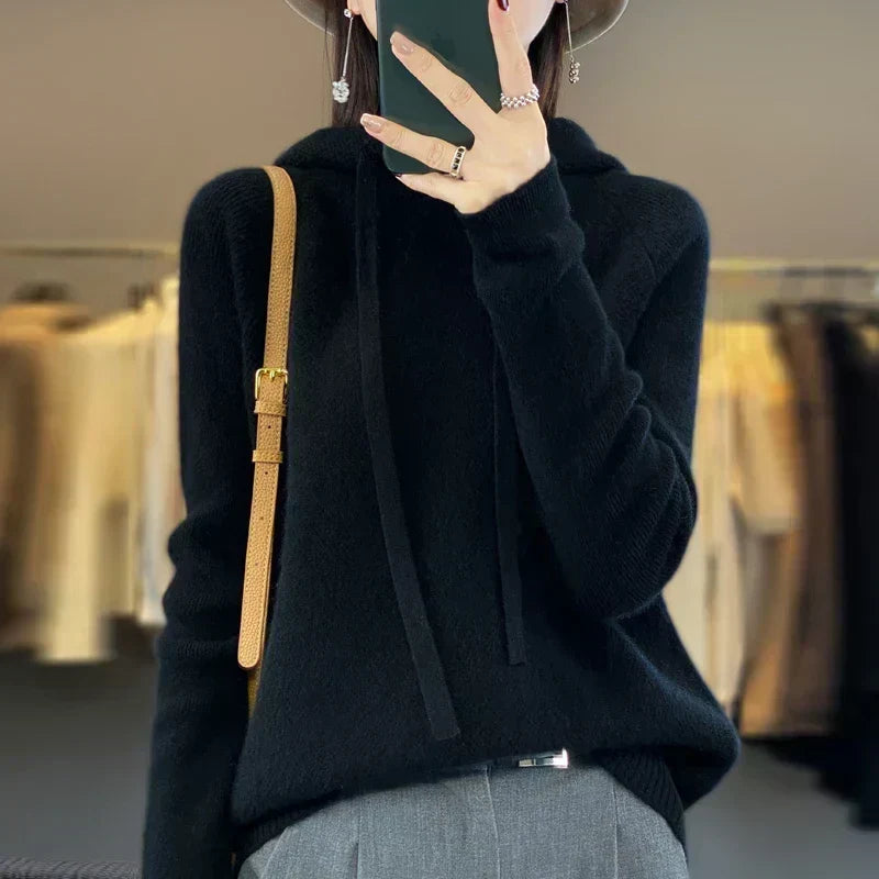 Nyelle knitted hoodie in black, worn with grey trousers