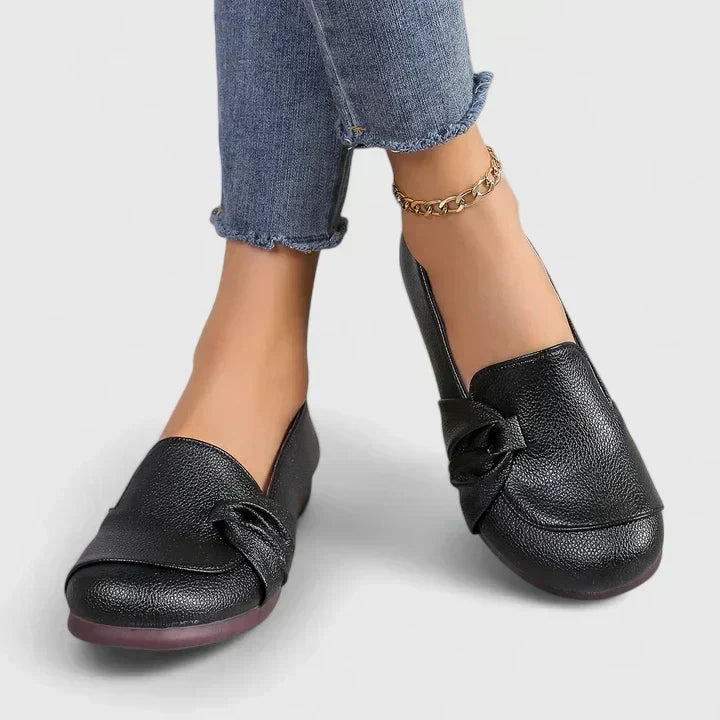 Lillian slip-on flat shoes in black, worn front view with knotted toe detail