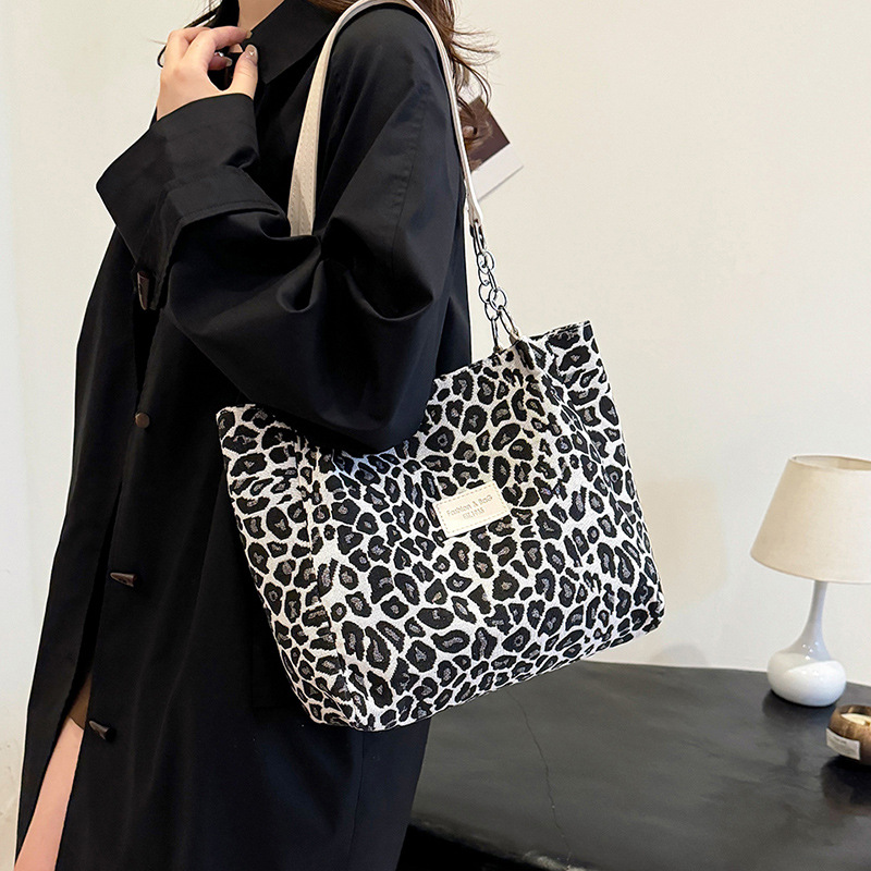 Snow leopard tote bag worn over the shoulder with black coat