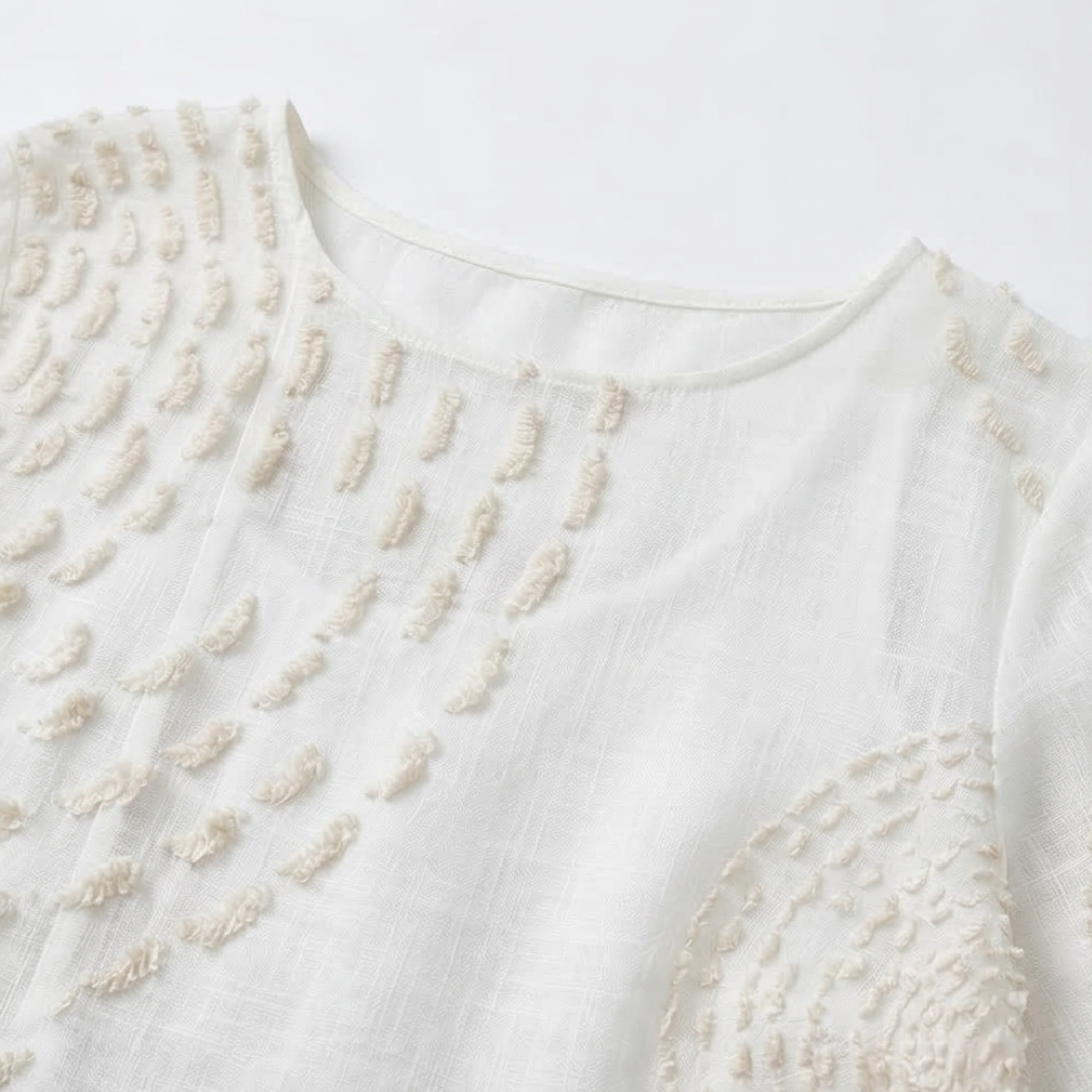 White embroidered dress, close-up of round neckline and tufted detail