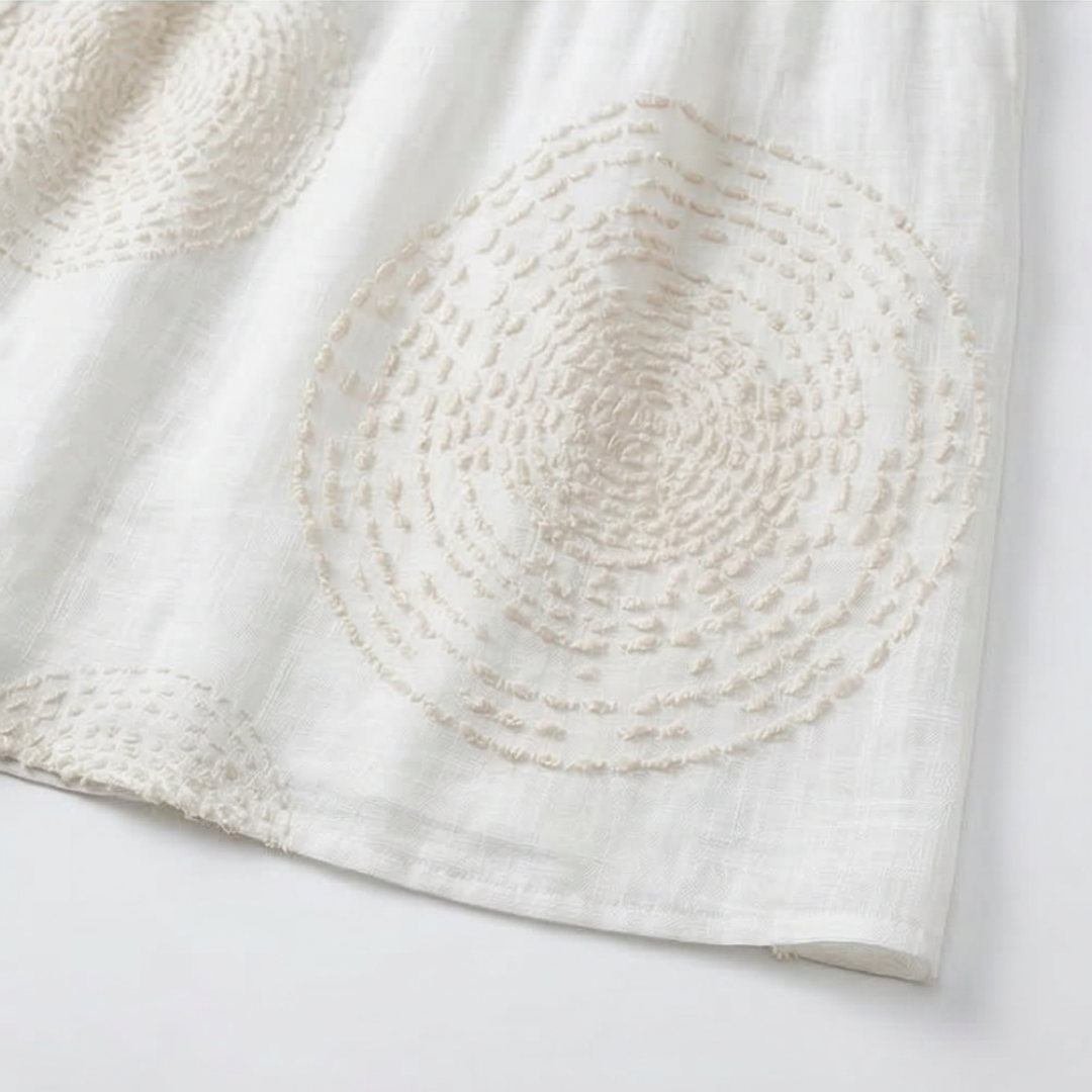 White embroidered dress, close-up of circular embroidery on the skirt