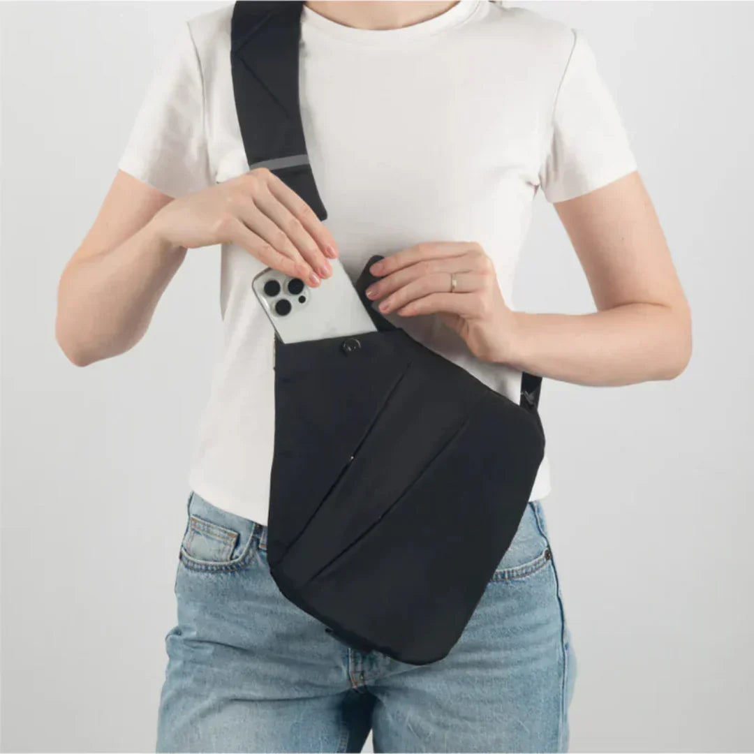 Orviane crossbody bag in black worn across the body, phone slipped into hidden pocket
