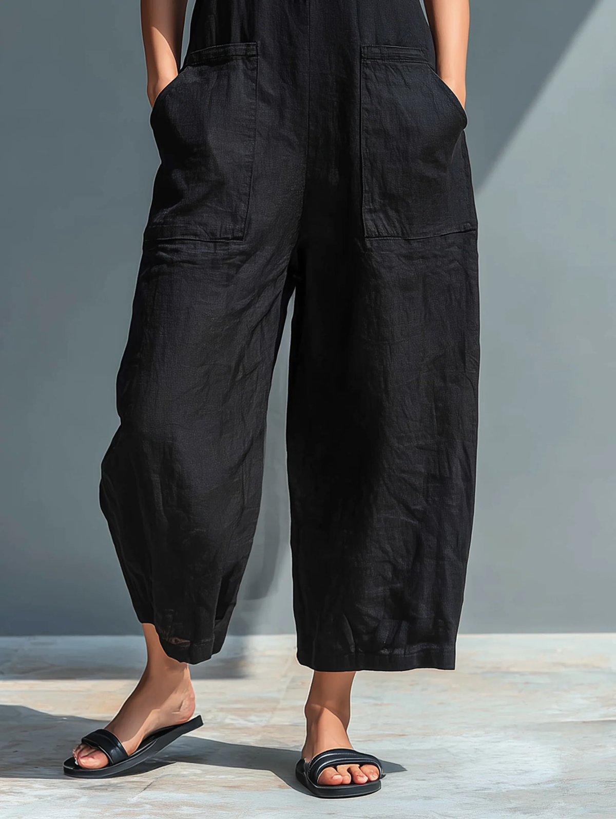 Lila sleeveless jumpsuit in black, close-up of wide-leg hem and pockets