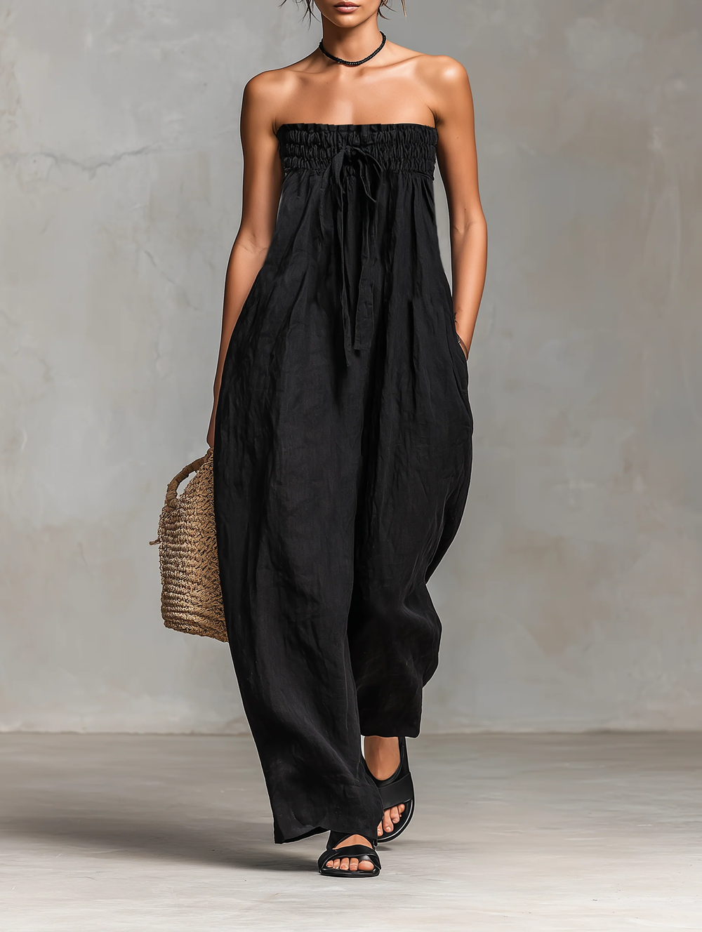 Lila strapless jumpsuit in black, full-length front view with straw basket bag