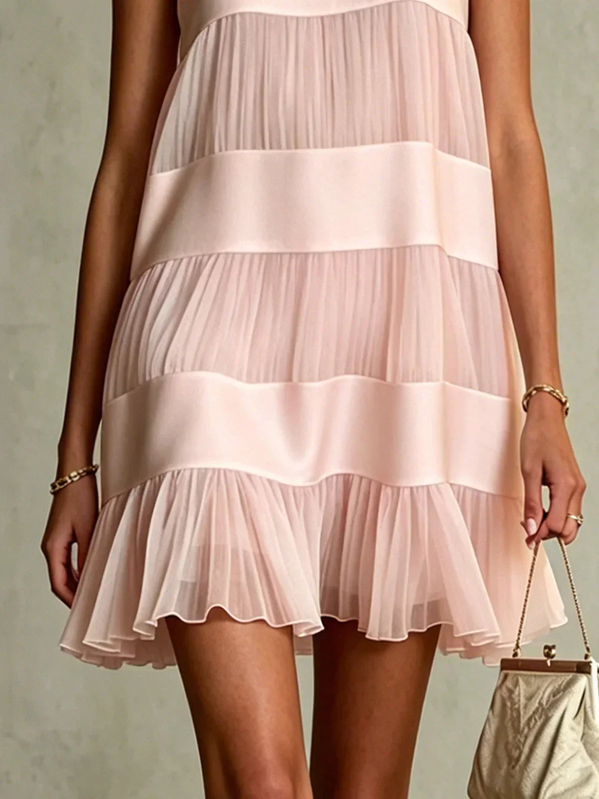 Close-up of gathered ruffled hem on light pink layered mini dress