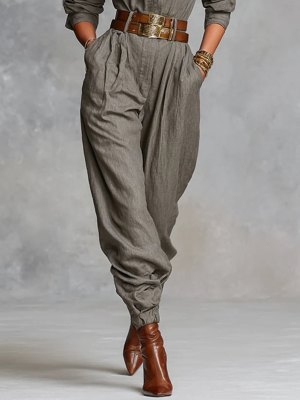 Long-sleeve jumpsuit in taupe, close-up of pleated tapered legs