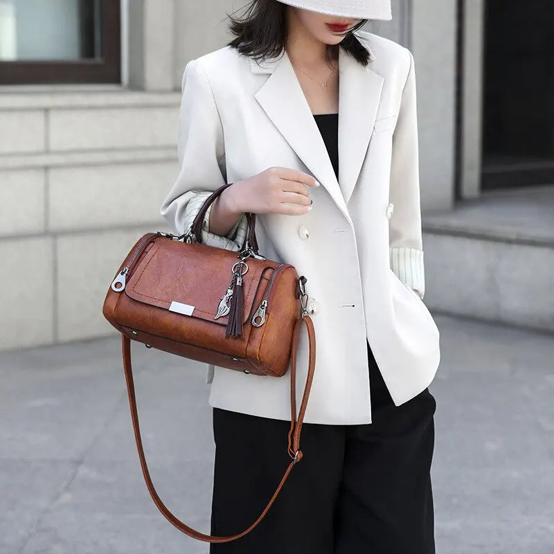 Eliana shoulder bag in brown carried by a model in a white blazer