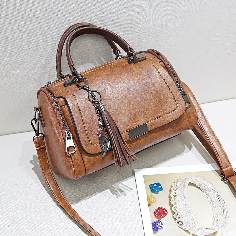 Eliana leather shoulder bag in brown, side view showing zip pockets