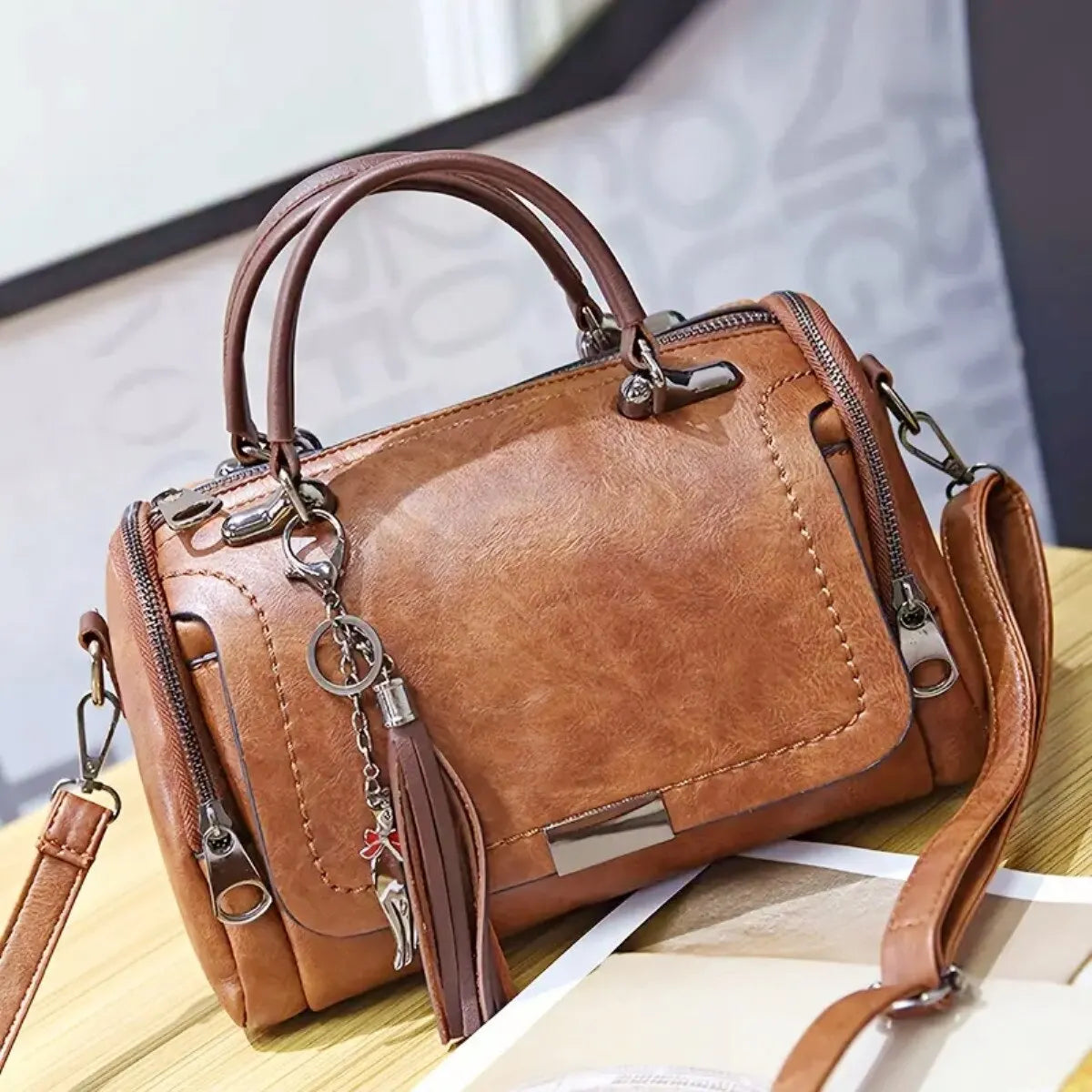 Eliana leather shoulder bag in brown, front view with tassel charm